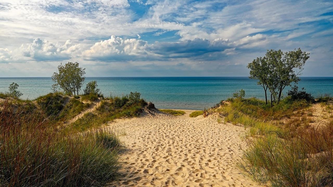 A sand path through dune grass opening onto Lake Michigan at the Indiana Dunes