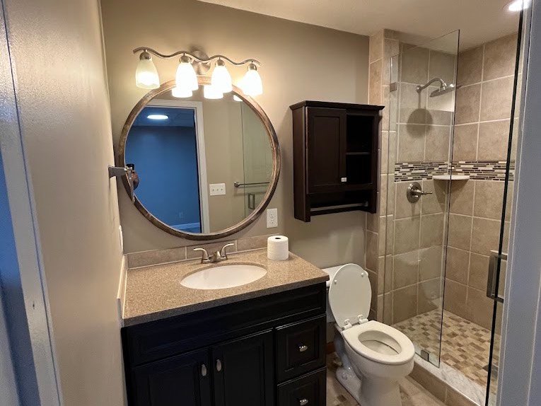 Cleaned bathroom with polished mirror, vanity and tiled shower