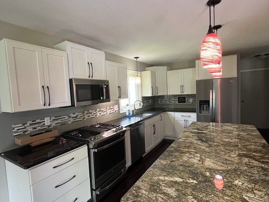 Kitchen with white cabinets and a polished granite island after a clean